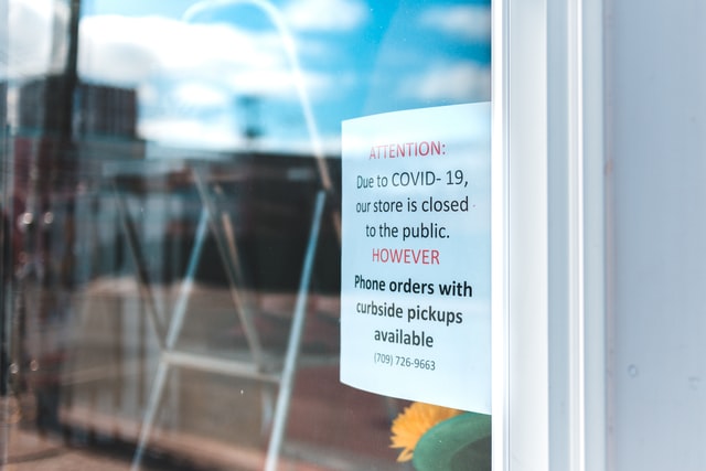 Photo of a shop window with a sign stating that the shop is closed due to covid-19.